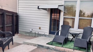 A house with a covered patio, a door, and two wicker chairs. - Charming 3-bedroom townhome, BMT Lackland, near SeaWorld, & 15mins to Downtown (San Antonio)