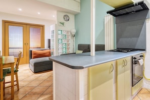 Una cocina compacta con estufa, horno y un pequeño comedor con mesa y sillas.