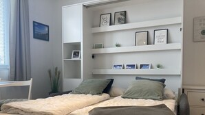 A bedroom with two beds, a desk, and shelves with framed photos and plants. - Strandnixe - A little time out - A little time out for relaxing days... Beach - and (Dahme)