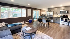 A modern kitchen with stainless steel appliances, a dining area with a table and chairs, and a living room with a sofa and a coffee table. - Charming 2-bedroom at Issaquah Front St (Issaquah)