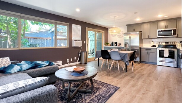 A modern kitchen with stainless steel appliances, a dining area with a table and chairs, and a living room with a sofa and coffee table. - Charming 2-bedroom at Issaquah Front St (Issaquah)