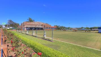 A sports field with a building in the background, a fence, and a clear sky.