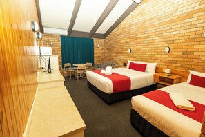 A hotel room with two beds, a desk, a chair, a table, and a TV.