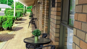 Un espace extérieur aménagé, abrité et doté de murs en briques, de plantes en pot, ainsi que de tables et de chaises.