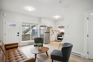A modern apartment with a living room, kitchen, and a staircase leading to an outdoor area. - Private 1BR Suite, New Build, 2 Guests, No Smoking (North Vancouver)