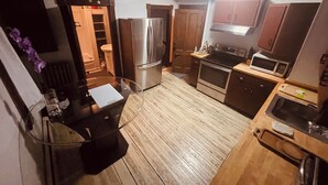 Une cuisine compacte avec un plancher en bois, un réfrigérateur, un four à micro-ondes, un évier et des placards.