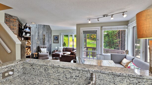 A spacious living area with a large window, a fireplace, and a dining table.