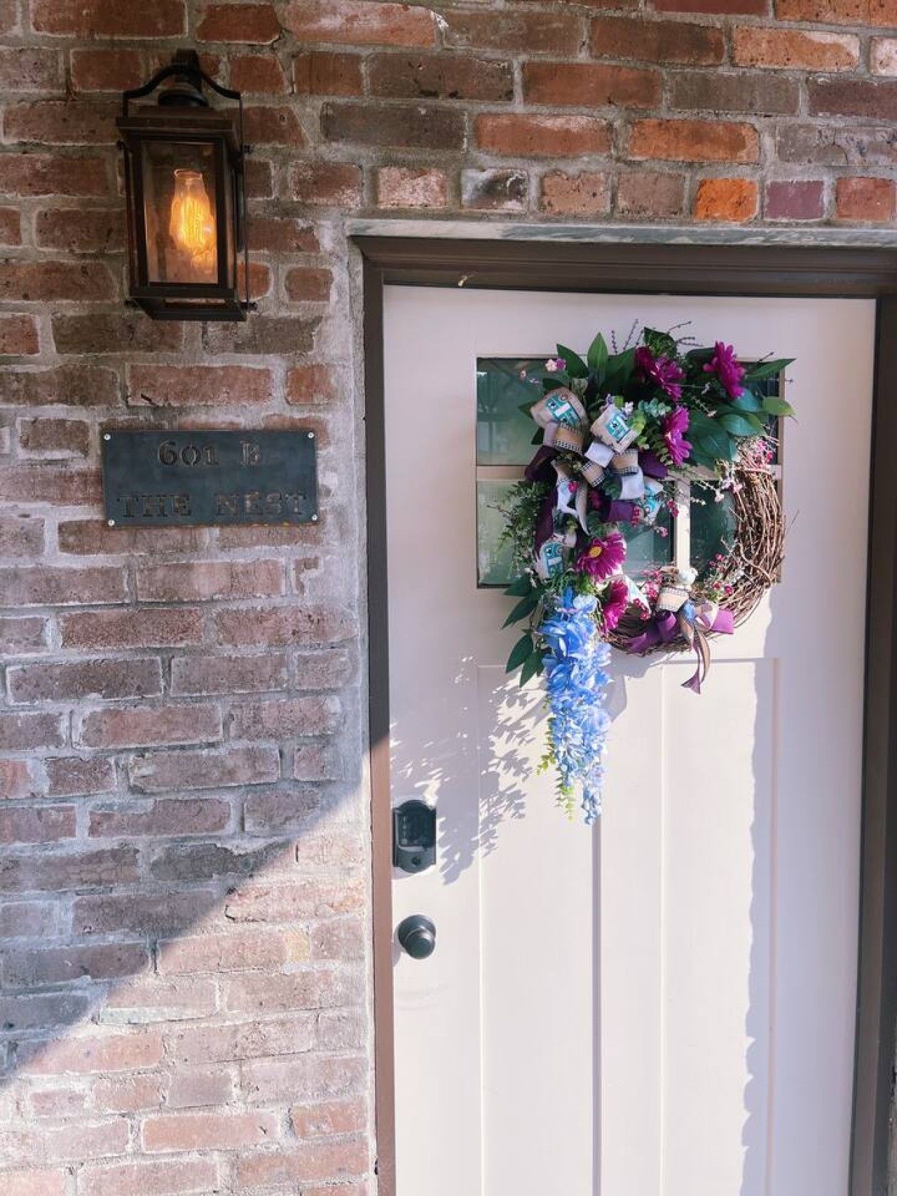 A brick wall with a door, a lantern, and a sign reading '601 B THE NEST.'