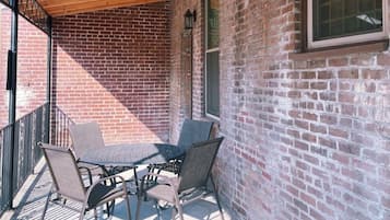 A covered patio area with a brick wall, a table with chairs, and a window.