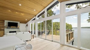A spacious living area with a large sliding glass door leading to a deck overlooking a lake.