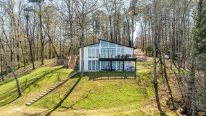 A modern house with a large glass facade, surrounded by a forest.