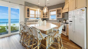 A kitchen with a large island, wicker chairs, and a view of the ocean. - Oak Rest Barn, is a custom built gulf front home w/pool, pet friendly, $250 credit for beach gear! (Port Saint Joe)