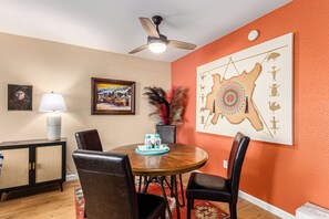 Cozy dining area with a round table and four comfortable chairs, featuring a unique artwork and a framed painting.
