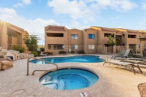 Relax by the pool surrounded by a deck and lounge chairs, with a small waterfall nearby.