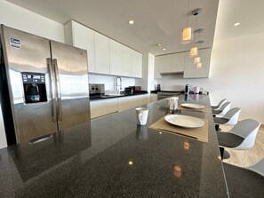 A modern kitchen with stainless steel appliances, a central island with seating, and pendant lighting.