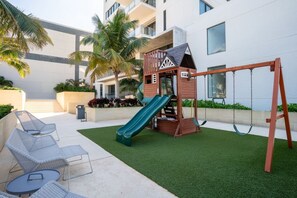 A children's play area with a slide, swings, and seating.