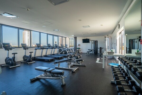 A gym with treadmills, stationary bikes, and free weights.