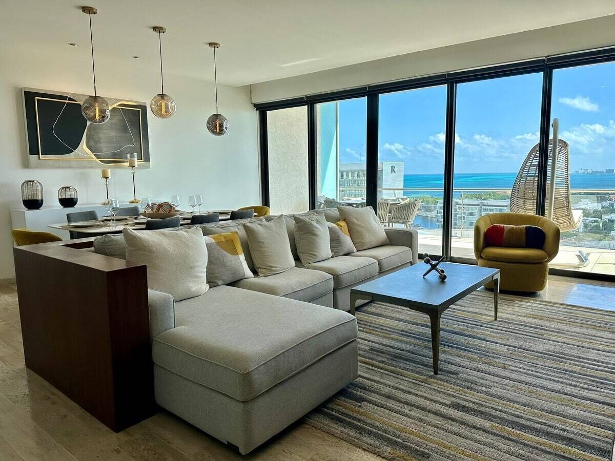 A modern living room with a sectional sofa, a coffee table, and a dining area with a table set for four.