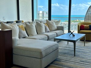 A modern living room with a sofa set, a coffee table, and a view of the ocean.