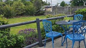 Un patio con sillas y una mesa de metal azul, rodeado por una cerca de madera y follaje.