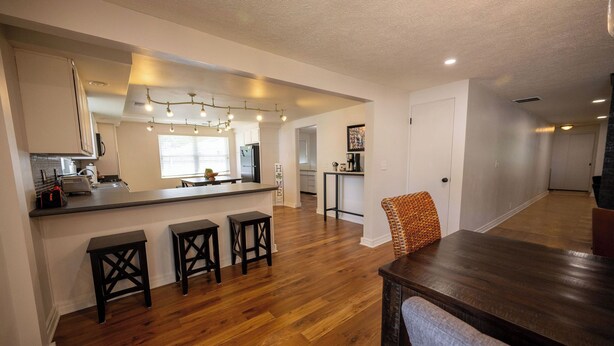 A modern kitchen with wooden flooring, a central island, and bar stools. - Vacation home, < 1 mile to University of Notre Dame, walk, bike or drive! (South Bend)