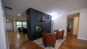 A living room with a fireplace, wooden flooring, and leather armchairs. - Vacation home, < 1 mile to University of Notre Dame, walk, bike or drive! (South Bend)
