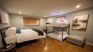 A room with two bunk beds, a small sofa, a wooden floor, and a painting on the wall. - Vacation home, < 1 mile to University of Notre Dame, walk, bike or drive! (South Bend)