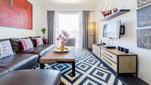 Un salon moderne avec un canapé, une table basse et un téléviseur.