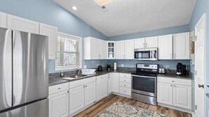 A modern kitchen with white cabinets, stainless steel appliances, and a patterned rug.