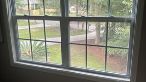 A window with a view of a residential area, including a lawn and trees. - Charming 1-bedroom apartment with WiFi, AC in enchanting Bluffton (Bluffton)