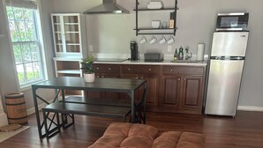 A spacious living area with a large brown leather ottoman, wooden flooring, a dining table, and a kitchen area with modern appliances. - Charming 1-bedroom apartment with WiFi, AC in enchanting Bluffton (Bluffton)