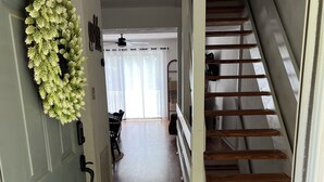 A hallway with a wooden staircase, a patterned rug, and a green door with a wreath. - Waterfront Townhome- with Boat Slip and Dock! (Moneta)