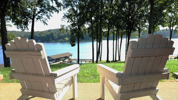 Two Adirondack chairs facing a lake with a picnic table and dock in the background. - Waterfront Townhome- with Boat Slip and Dock! (Moneta)