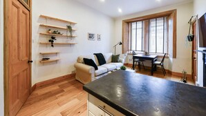 A cozy living room with a sofa, a dining table, and a kitchen area with a countertop. - GuestReady - Comfortable 1Bed in Leith (Edinburgh)