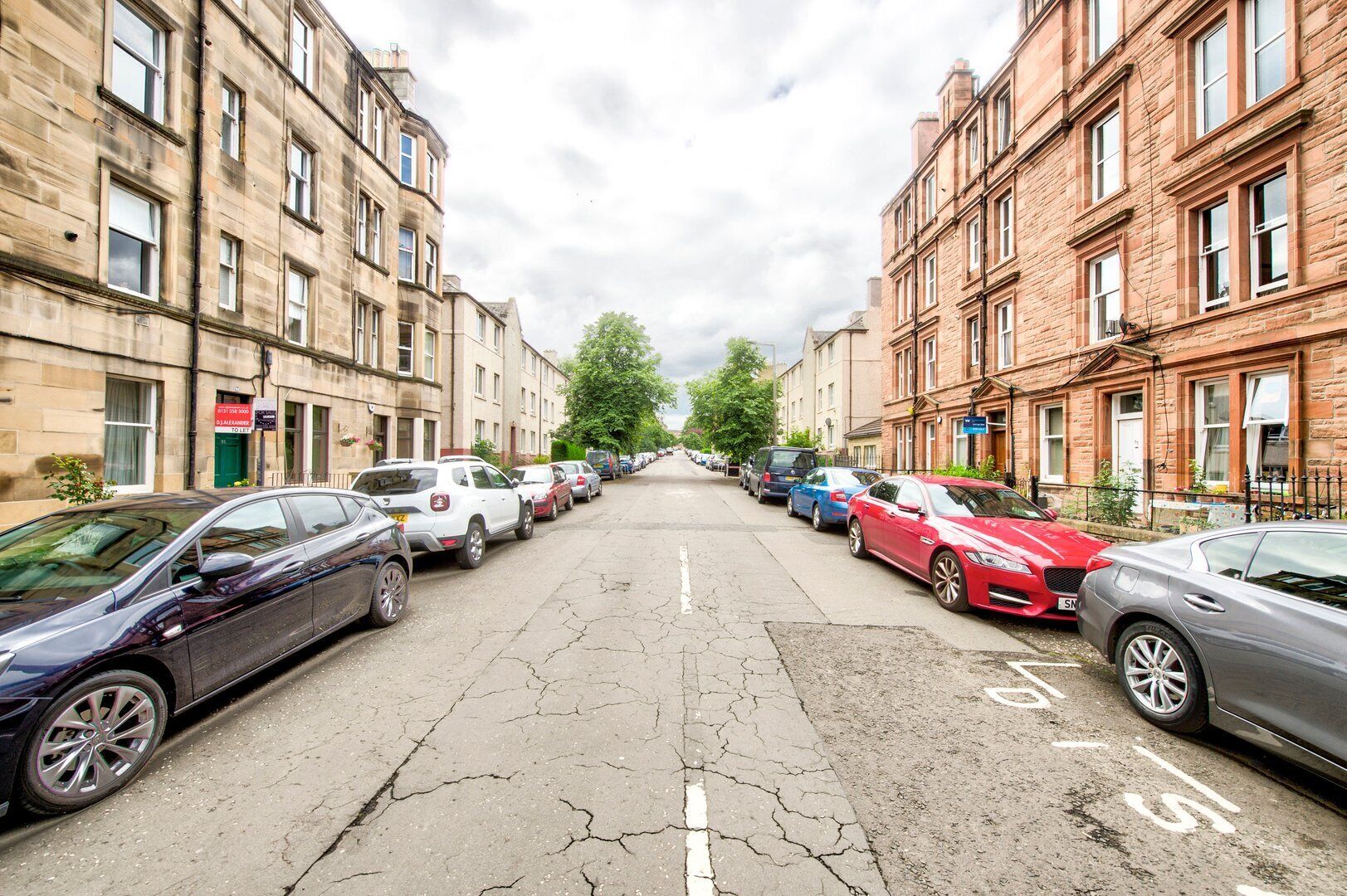 A street lined with parked cars and buildings on both sides.
