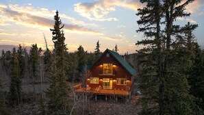 A log cabin with a green roof, surrounded by dense forest. - Horseshoe Hideaway with Sunset Views (Jefferson)