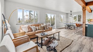 A spacious living area with a leather sofa, a wooden coffee table, and a large window offering a view of trees. - Horseshoe Hideaway with Sunset Views (Jefferson)