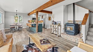 A spacious living area with a wooden bench, a sofa, and a dining table. A stone fireplace is visible in the background. - Horseshoe Hideaway with Sunset Views (Jefferson)