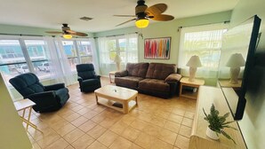 A living room with a sofa, armchairs, a coffee table, and a ceiling fan.