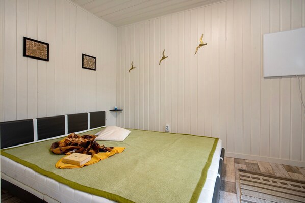 Un dormitorio con cama, almohadas, una colcha y decoración en la pared.