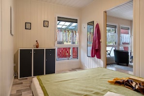 A room with a bed, a wardrobe, a window with curtains, and a view of the outside.