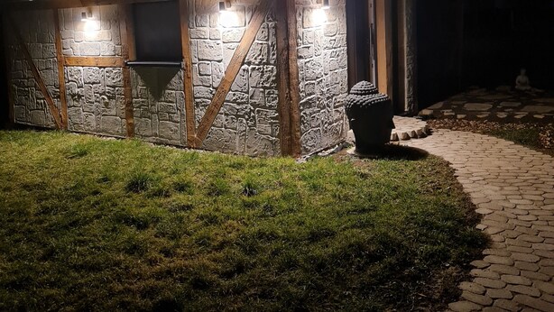 Un edificio de piedra con puerta y ventanas de madera, iluminado por luces exteriores.