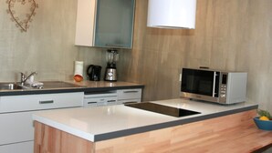 Una cocina moderna con microondas integrado, licuadora, lavabo y encimera de madera.