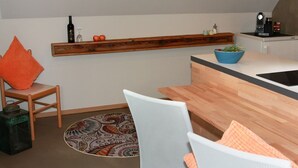 Una cocina moderna con encimera de madera, estante empotrado y comedor con silla y mesa.