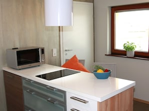A kitchen with a microwave, a sink, a window with a plant, and a door.