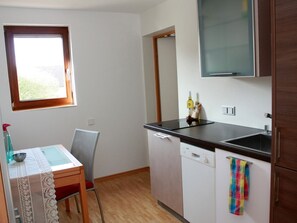 A compact kitchen with a window, a dining table with a chair, a dishwasher, and a cabinet. - Apartment 'Nelly' with Wi-Fi (Bisingen)