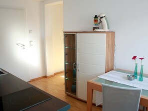 A modern kitchen with a built-in oven, a glass cabinet, and a dining table with a vase of flowers. - Apartment 'Nelly' with Wi-Fi (Bisingen)