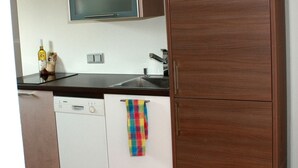 A kitchen with a microwave, a dishwasher, and a colorful towel hanging on the door.