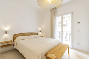 A bedroom with a bed, bedside tables, a bench, a ceiling light, and a sliding glass door to the outside.