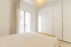 A bedroom with a bed, a wardrobe, and a door leading to a balcony.